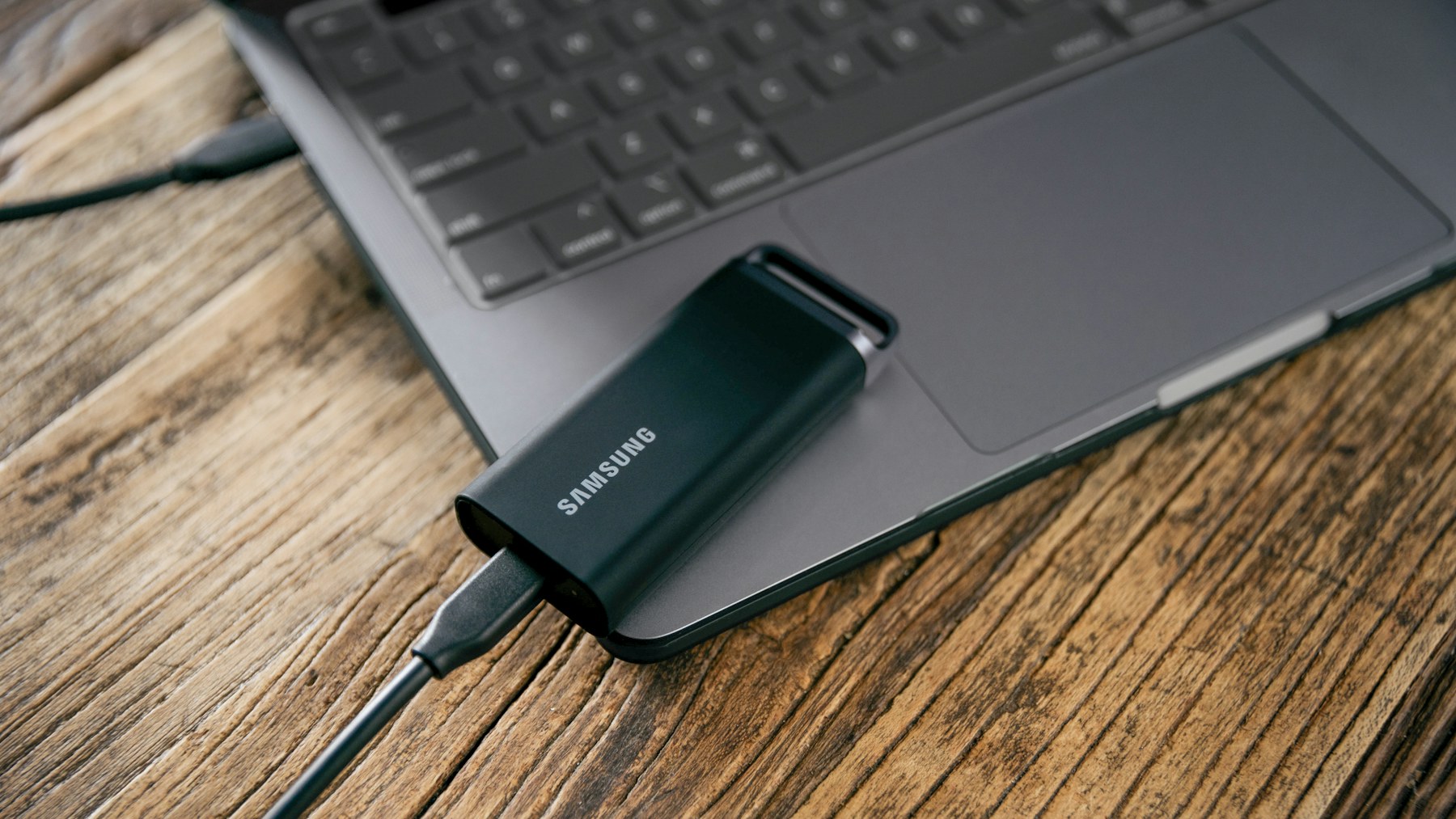 Portable SSD connected beside a laptop for project transfer and backup