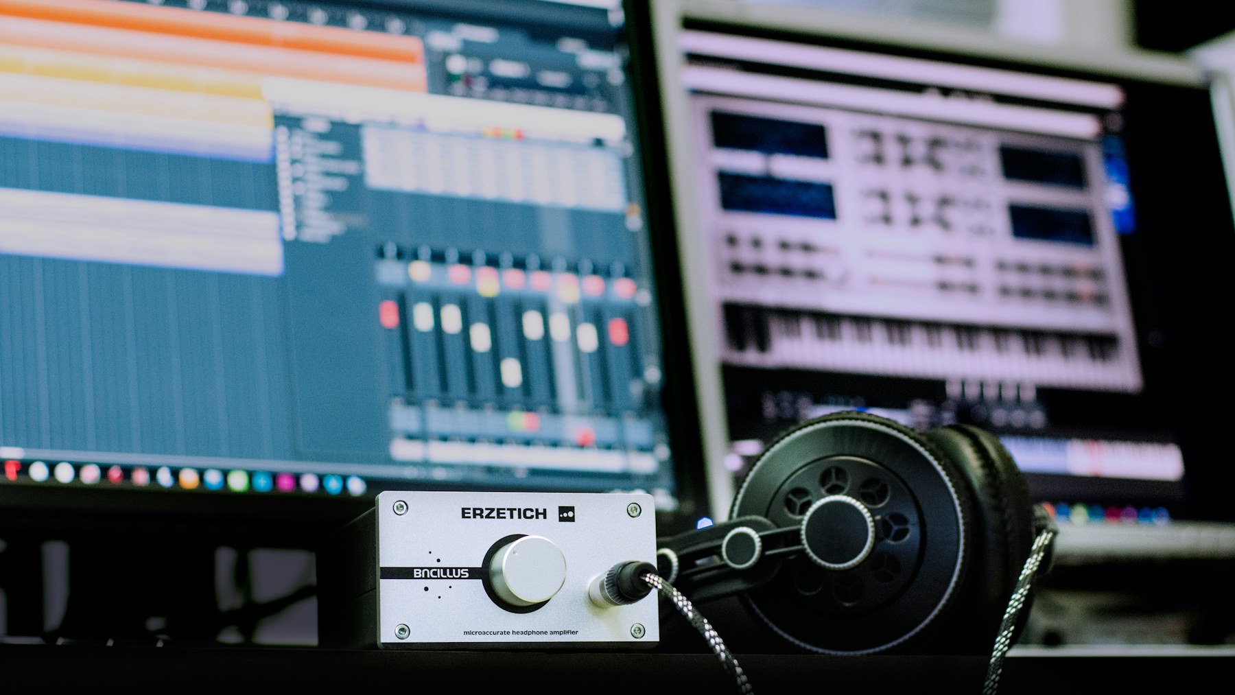 Headphones and a headphone amplifier in front of music-production software